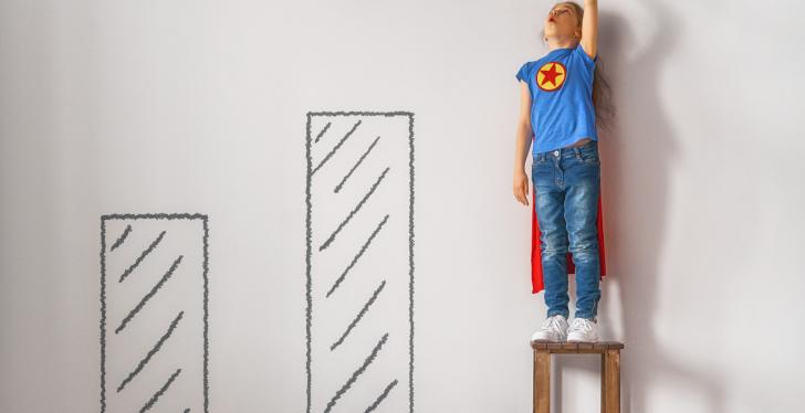 A child with a Superman costume stands on a chair