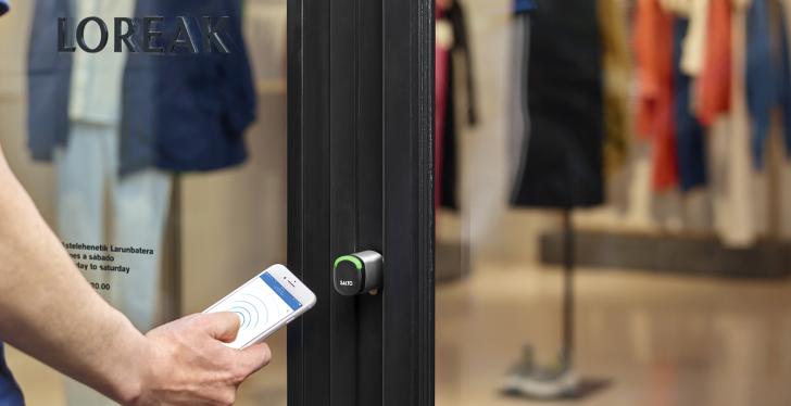 Person in front of store doors holds smartphone in hand. copyright: Salto...