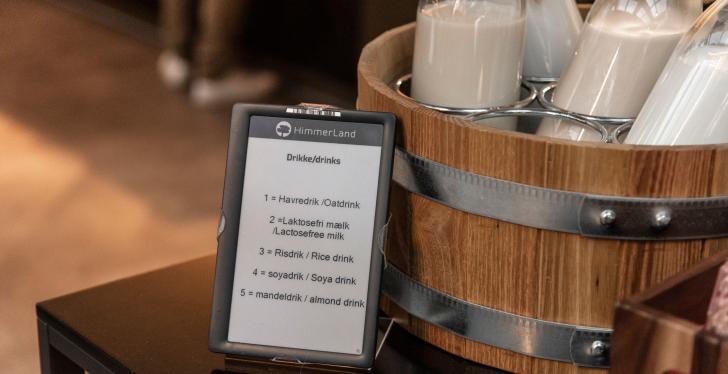 A digital sign in front of a bucket with milk bottles...