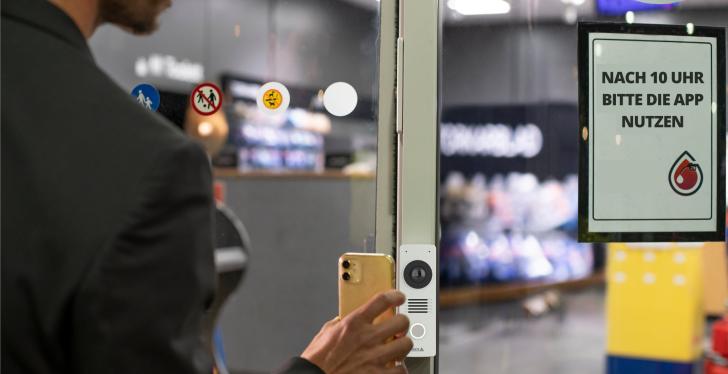 Smartphone is held in front of access control; copyright: Axis Communications...