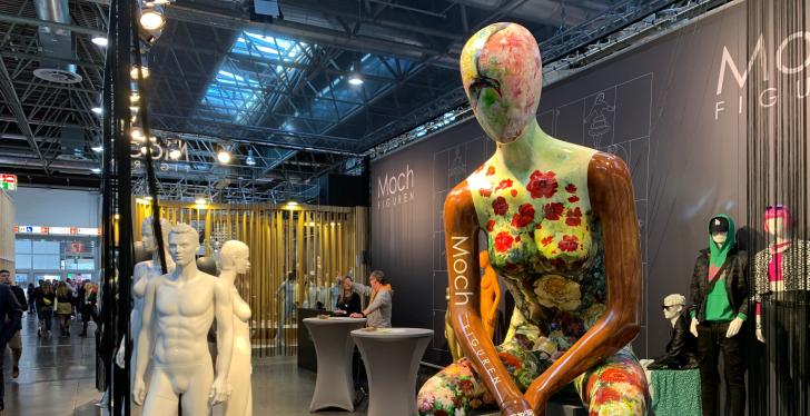 A sitting mannequin in an exhibition hall, painted with colourful flowers...
