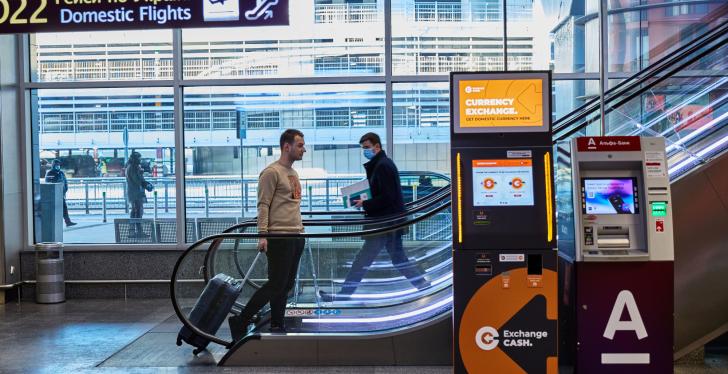 A currency exchange machine in front of an escalator...