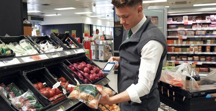 A person scans a bag of onions with a hand scanner