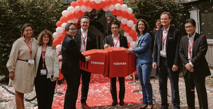 Several people standing in front of an arch of red and white balloons at an...