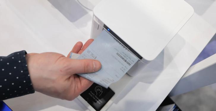 A hand takes a receipt from a receipt printer.