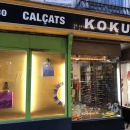 An illuminated shop window with a yellow background and two handbags and...