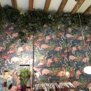 A clothing store with a wallpaper with flamingos and hanging ivy on the ceiling...