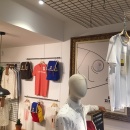 A black grille attached to the ceiling in a clothing store, from which a shirt...