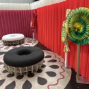 Round stools on round rugs in front of a red curtain....