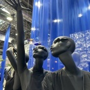 Two very slender, black mannequins striking elegant poses in front of a blue...