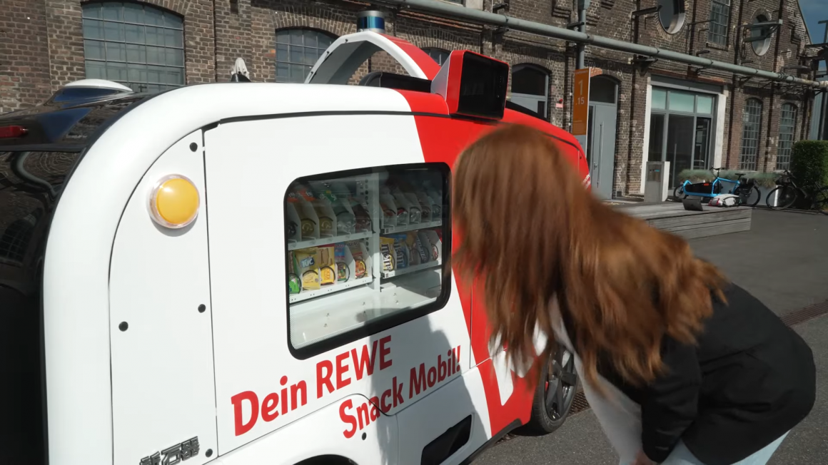 A woman stands in front of the self-driving kiosk and looks at the products...