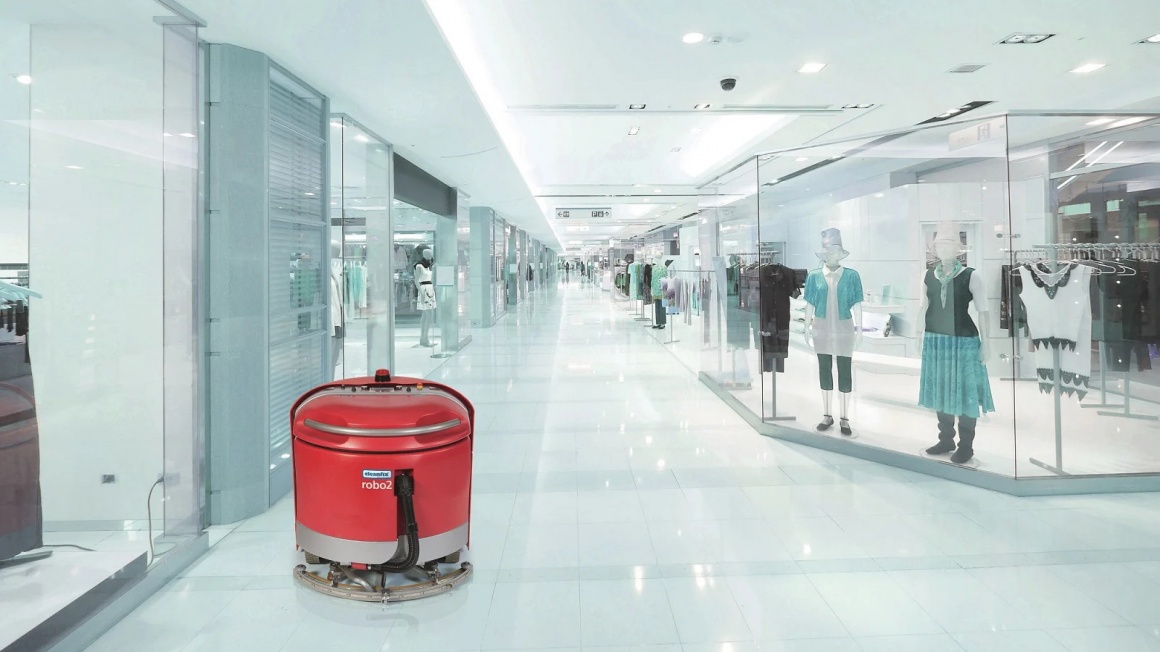 A red self-driving robot cleaning a floor in a retail space; copyright:...