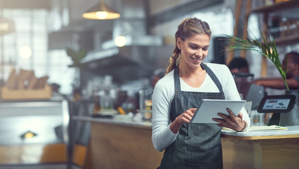 An employee in a catering business operates a tablet PC while leaning against...