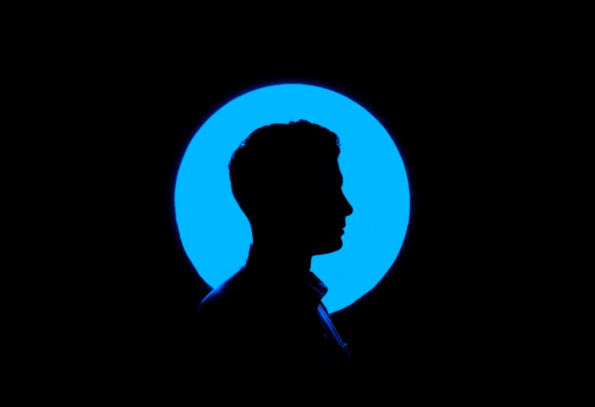 A black silhouette of a male head infront of a blue circle and a black...
