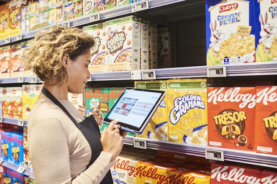 A person is using a tablet in front of a shelf