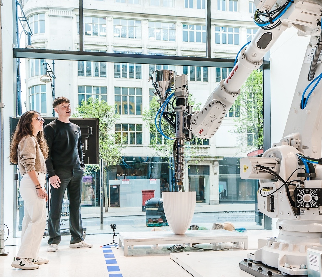 Two people looking at a big 3D printer