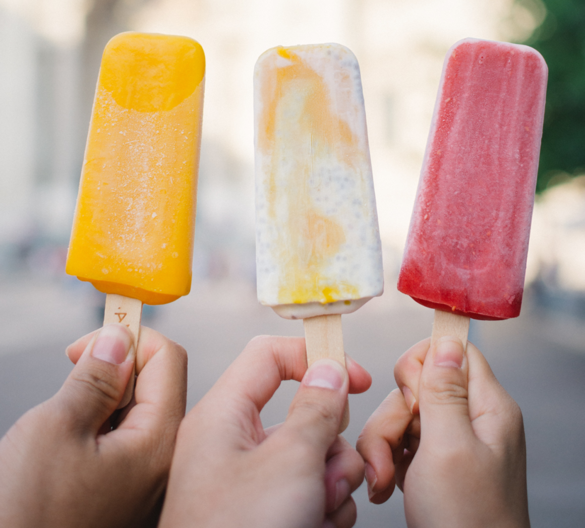 Three hands holding three popsicles