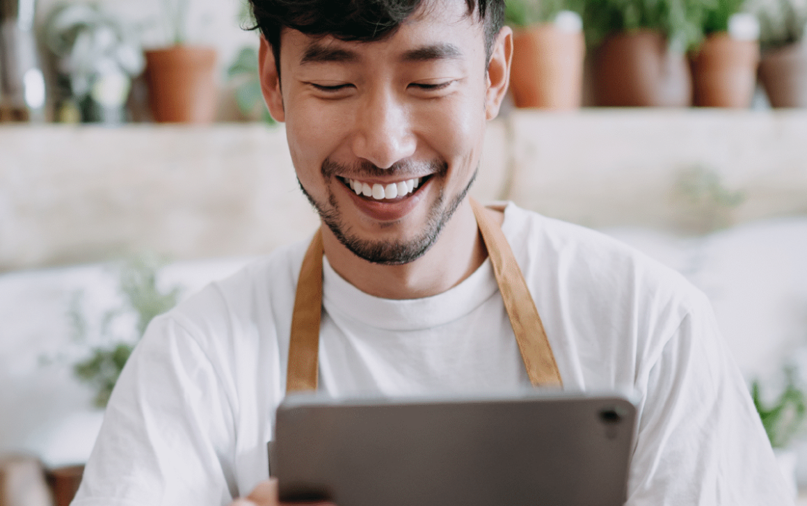 A man smiles while using a tablet