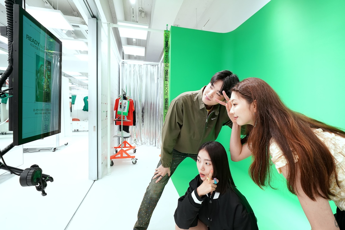 Three people in front of a greenscreen looking at a tv screen....