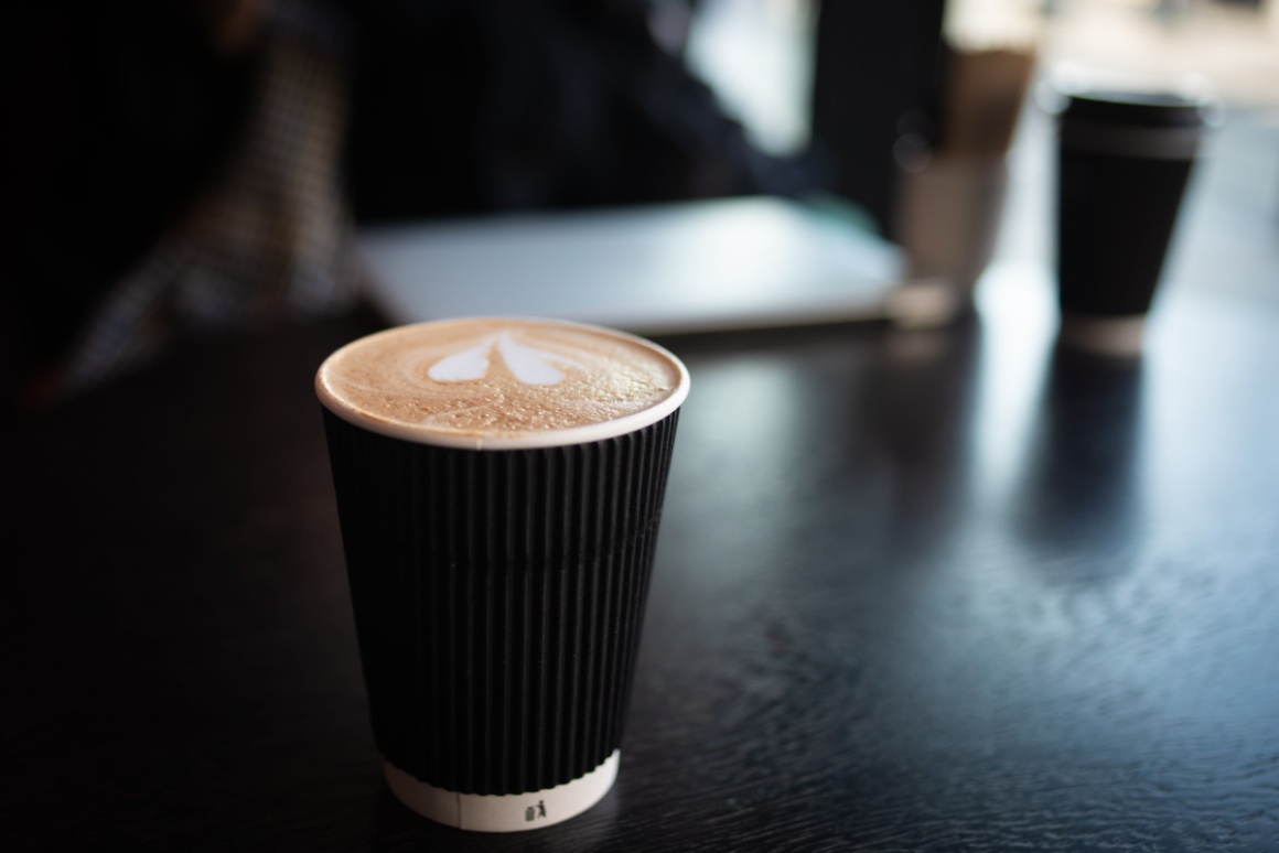 A black coffee to go mug on a dark table; copyright: Masaaki Komori/Unsplash...