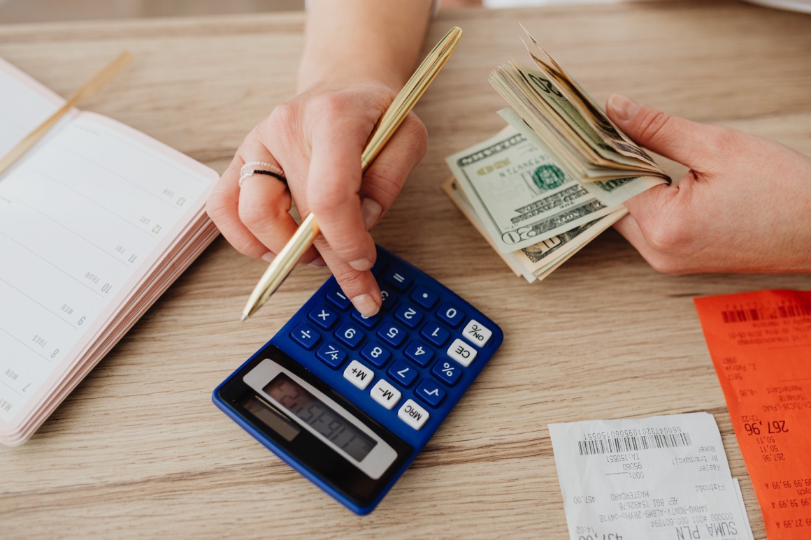 A person using a calculator while holding money