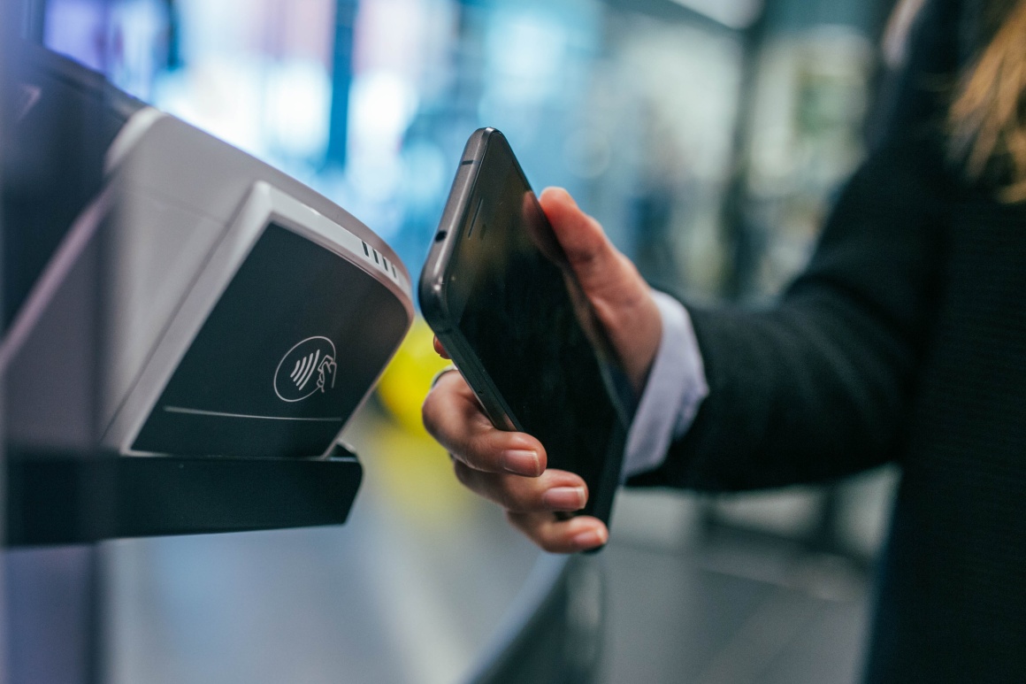 A person holds a smartphone up to a terminal for payment...