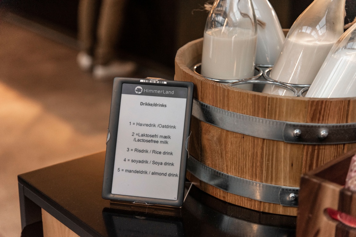 A digital sign in front of a bucket with milk bottles...