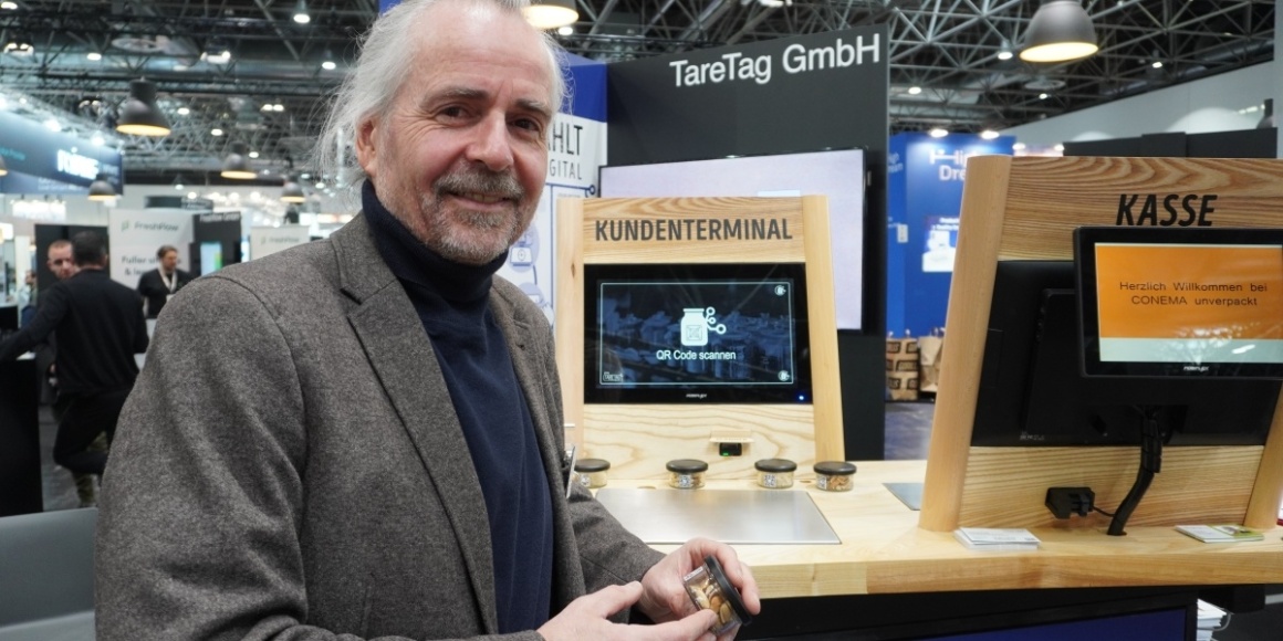 Man with gray hair and dark jacket in front of a customer terminal at EuroShop...