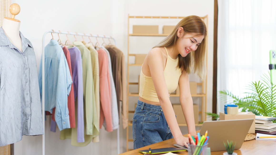 Woman standing in front of laptop in clothing store...