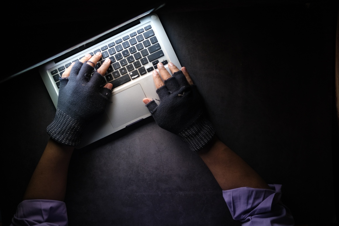 Two hands with gloves using a laptop