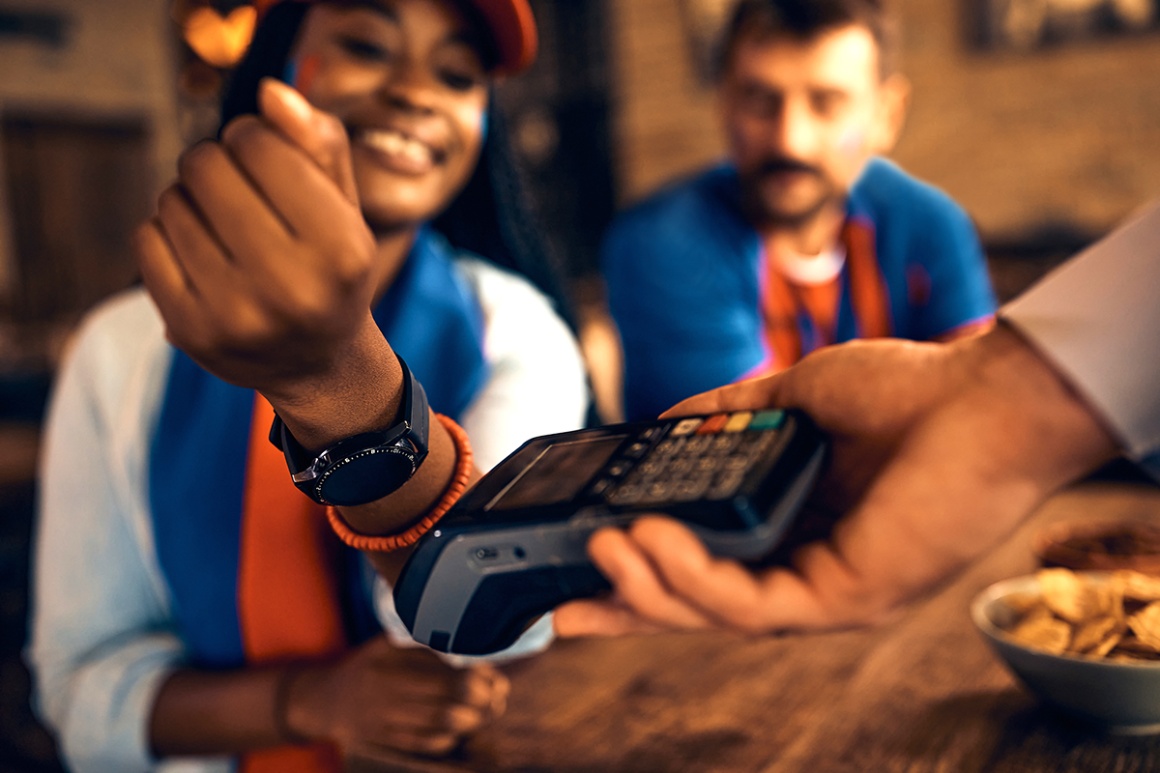 A person uses a smartwatch to pay at a card reader