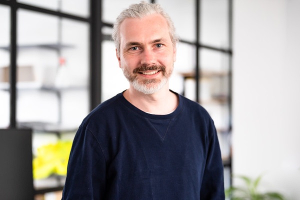 Man with grey hair and grey beard smiles at the camera...