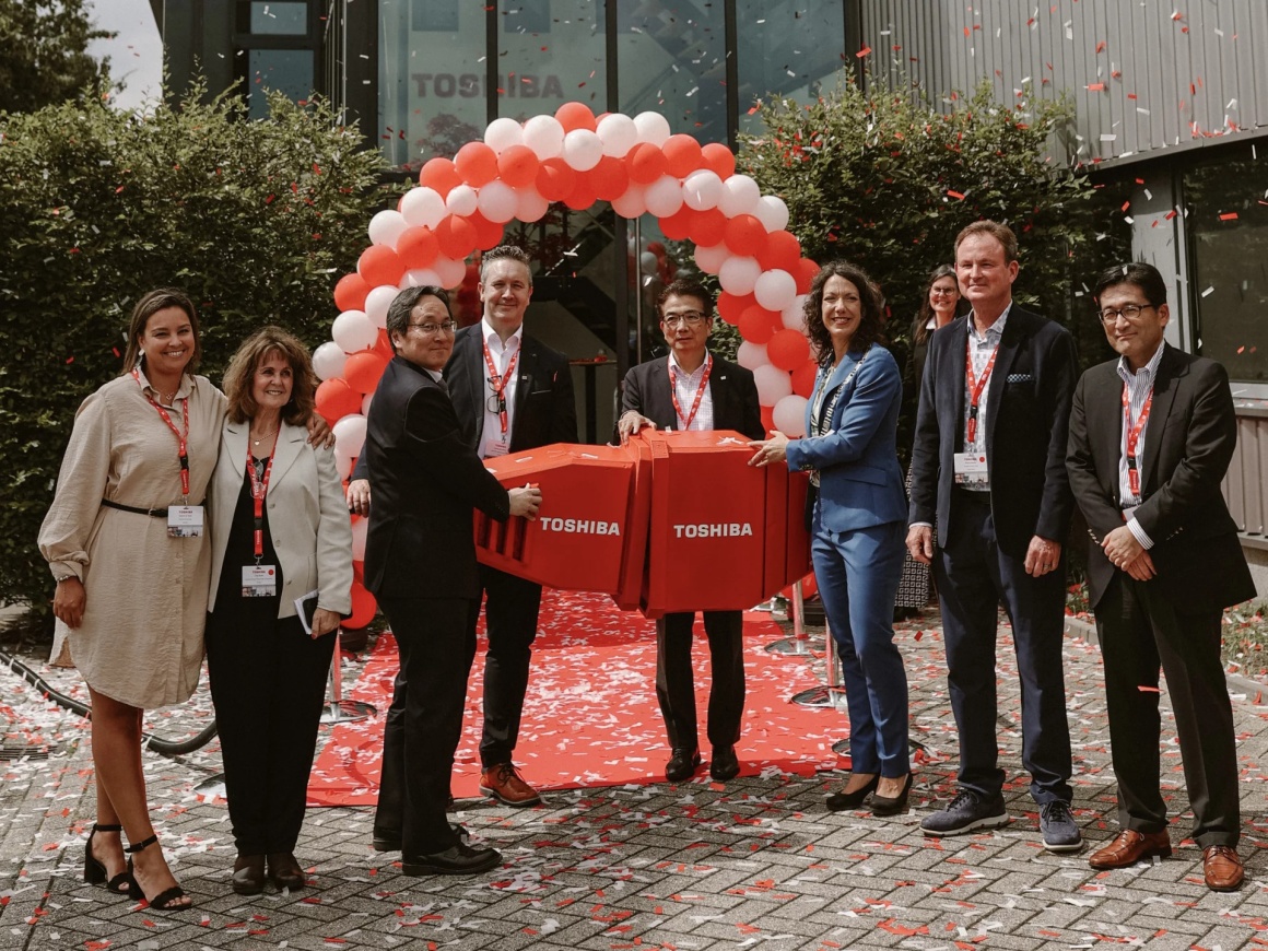 Several people standing in front of an arch of red and white balloons at an...