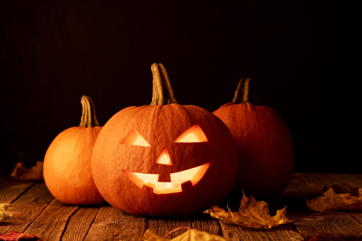 Three pumpkins, one with a carved face.