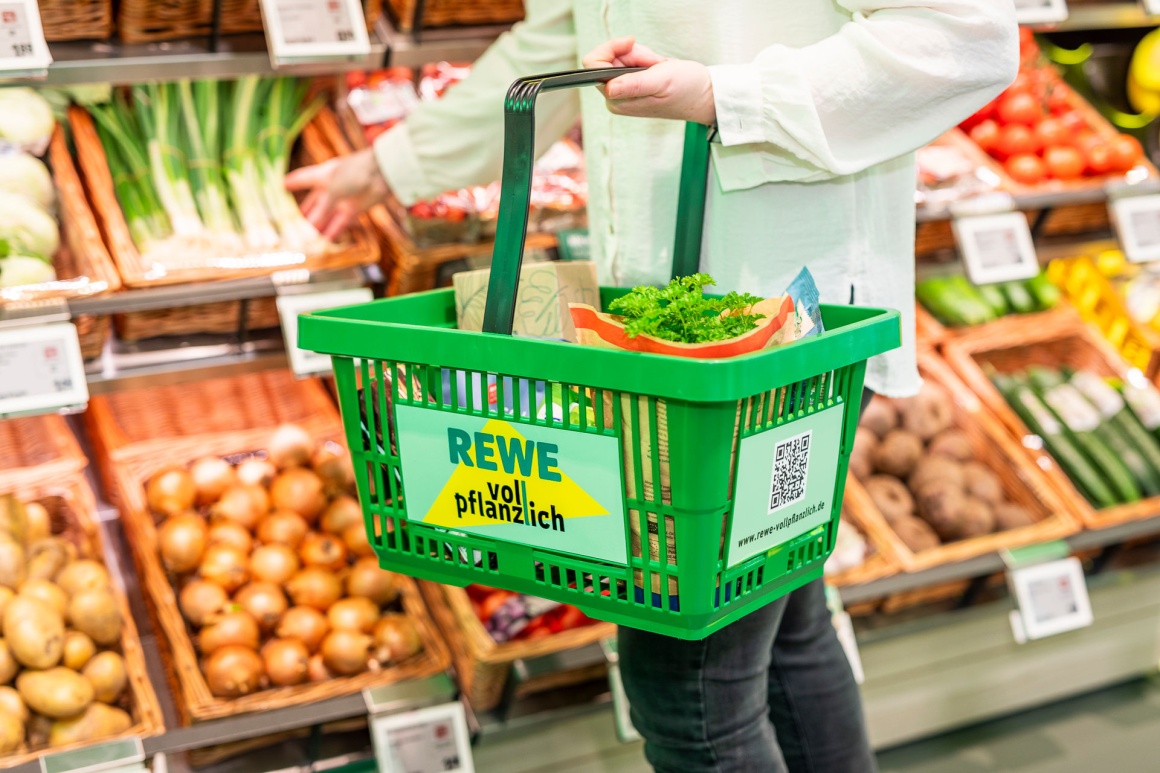 A person with a shopping basket in front of the vegetables...