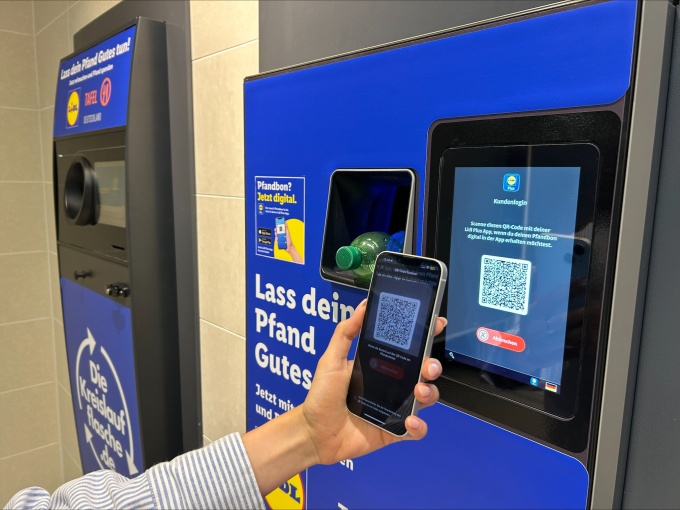 Hand holding a smartphone scans a QR code on a Lidl reverse vending machine to...