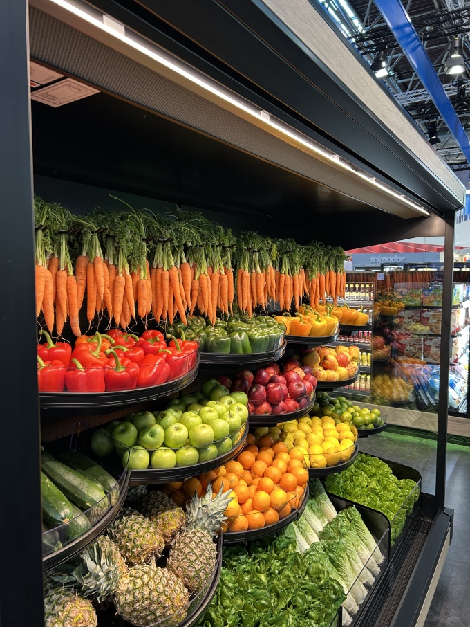Creatively arranged fresh produce, such as carrots hanging from hooks, in...