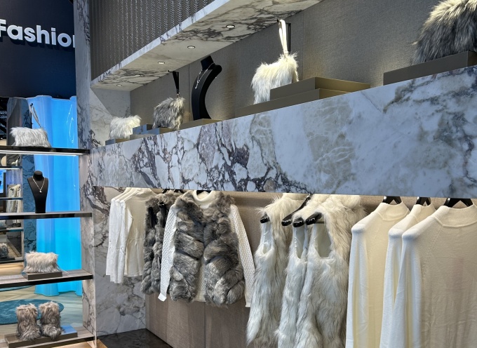 A clothes rack displaying high-quality-looking gray-white clothing in front of...