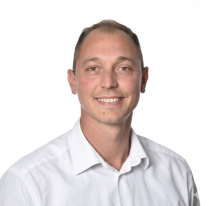 A man in a white shirt smiles at the camera.