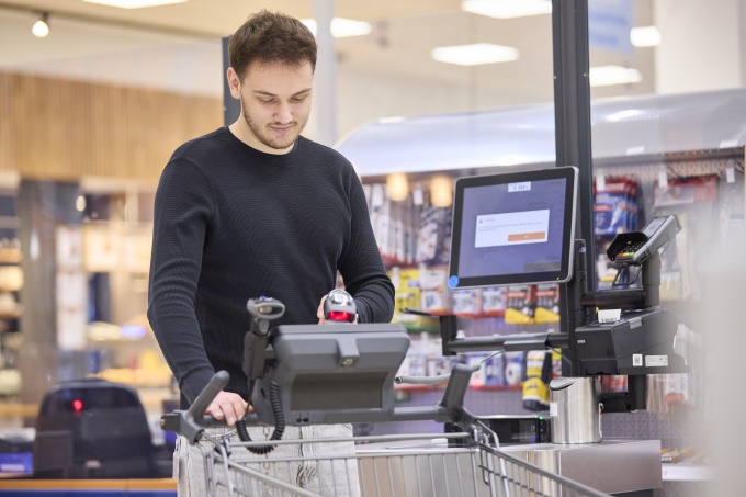 A man in a dark long-sleeved top is standing in the shopping centre with a...