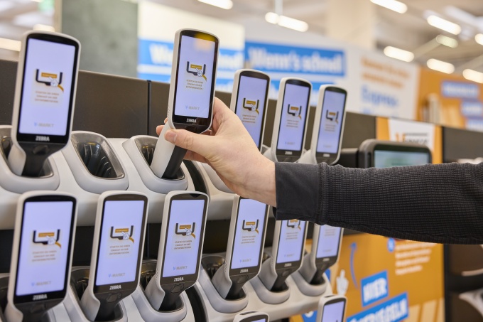 A person takes a hand-held scanner from the stand in the supermarket...