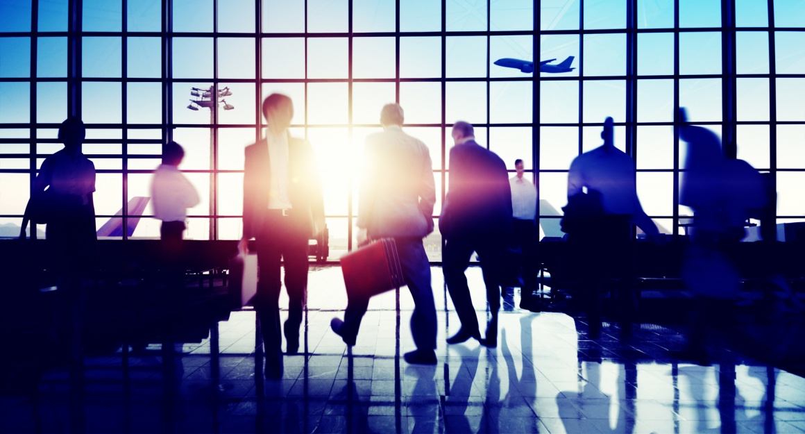 Photo: People walking around in air terminal with flying plane in background;...