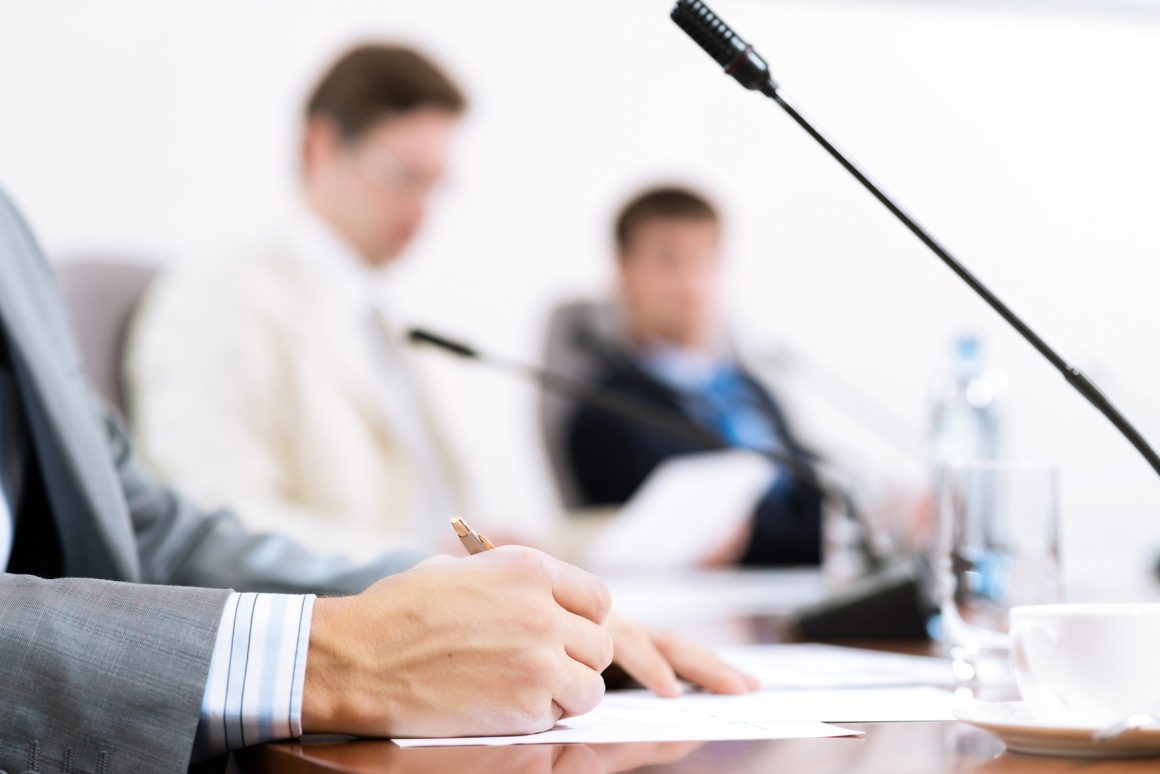 Photo: People sitting at a conference table with microphones; copyright:...