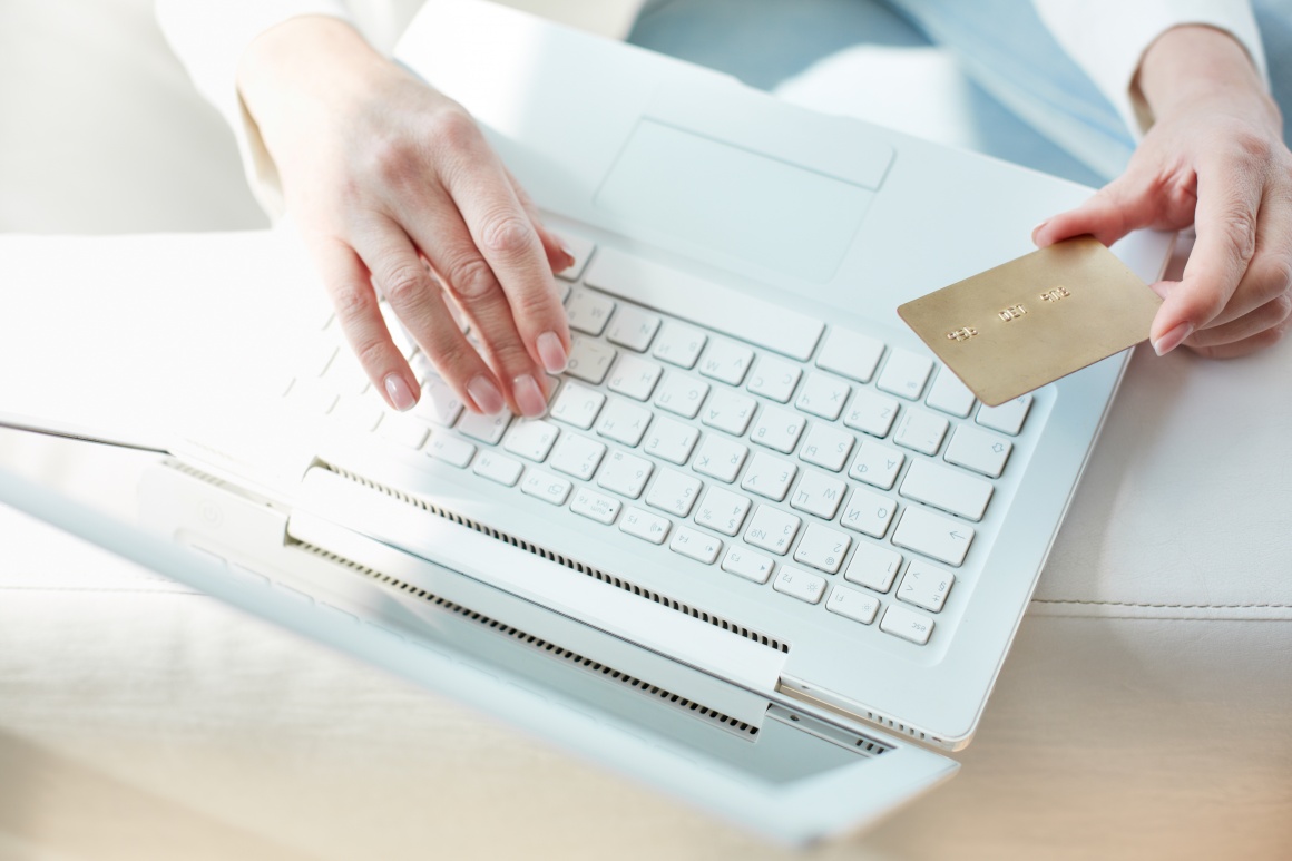 Hand holding credit card over a laptop