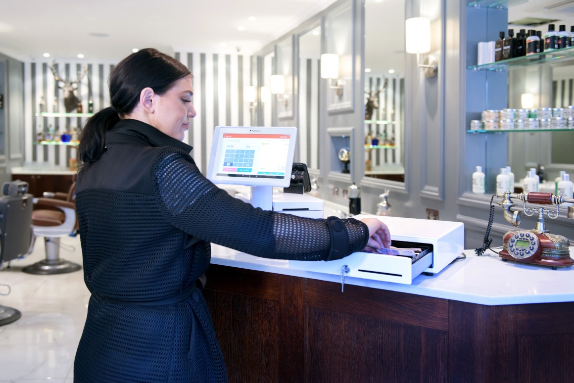 Photo: Woman handling the cash drawer on the counter of a hair salon;...