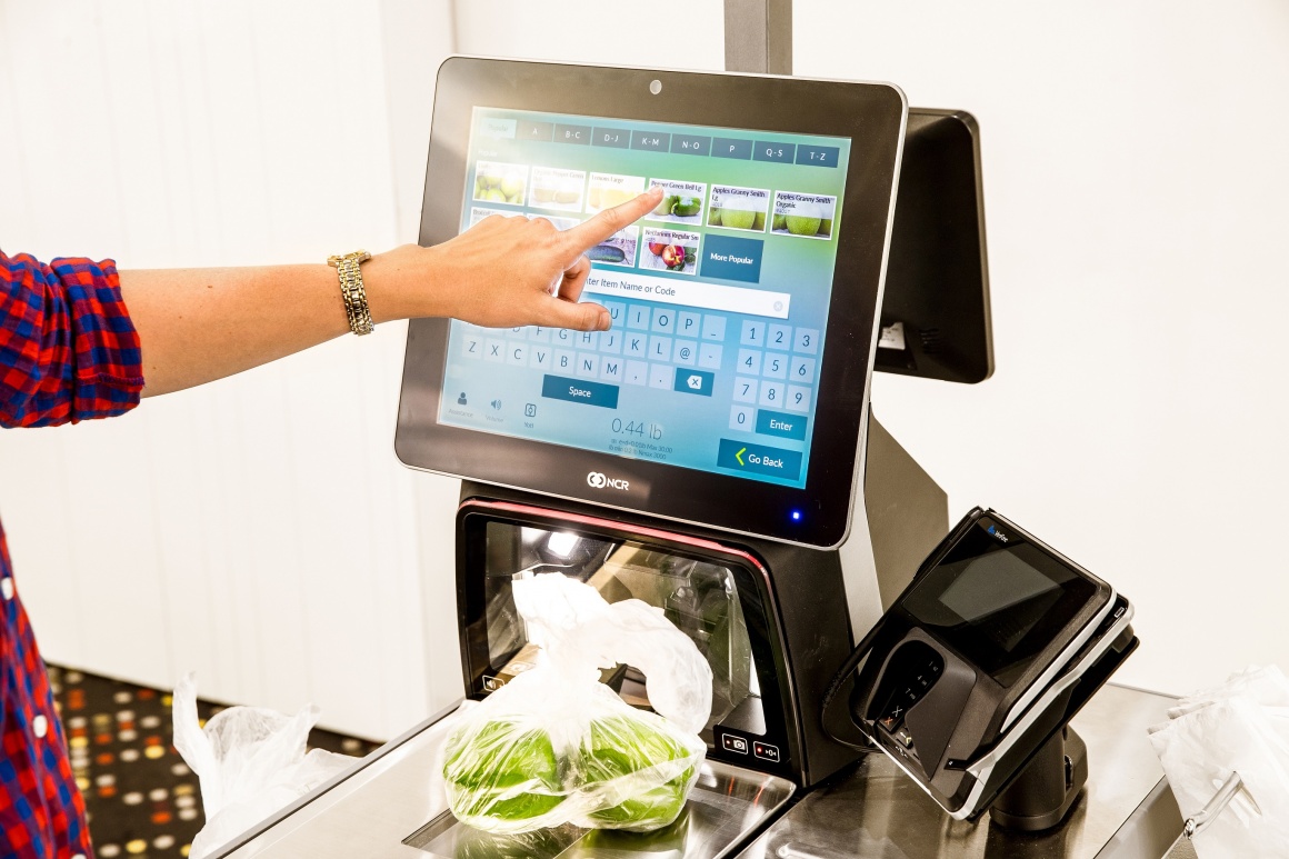 Photo: Person operating a self-checkout terminal; copyright: NCR GmbH...