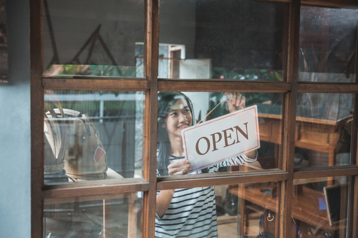 Photo: Woman hangs open sign in the shop window; copyright: panthermedia. net /...