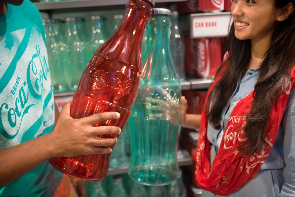 Two people holding big colored coca cola bottles; copyright: The Coca-Cola...