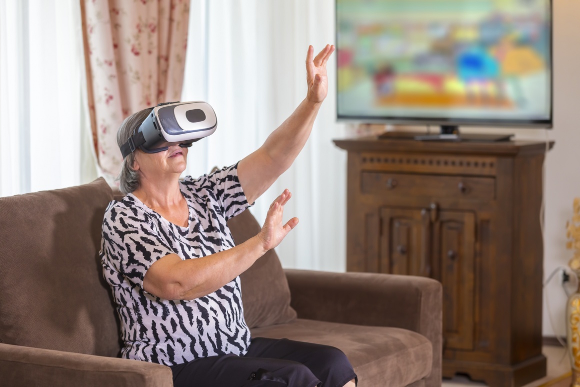 Older woman with VR glasses at home on the armchair; copyright:...