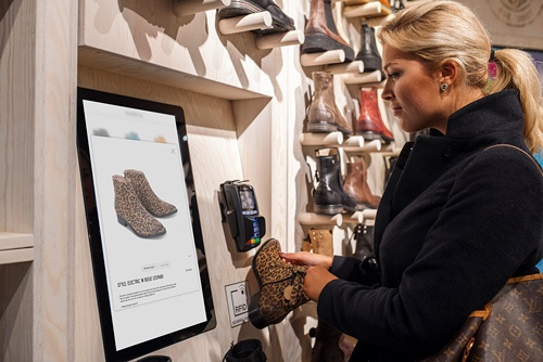 Woman using a touch screen in a store; copyright: Elo Touch Systems...